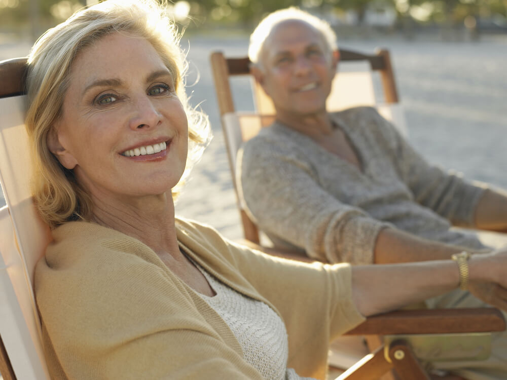 Older couple sitting in chairs holding hands