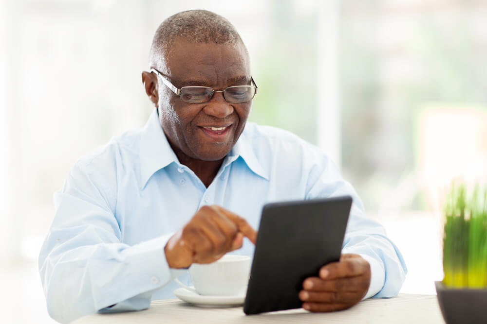 Man having a cup of coffee and using a tablet device